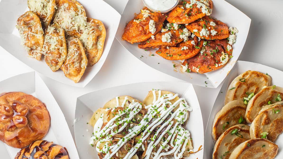 An overhead spread of dumplings, pierogi and a fried cheesecake bun